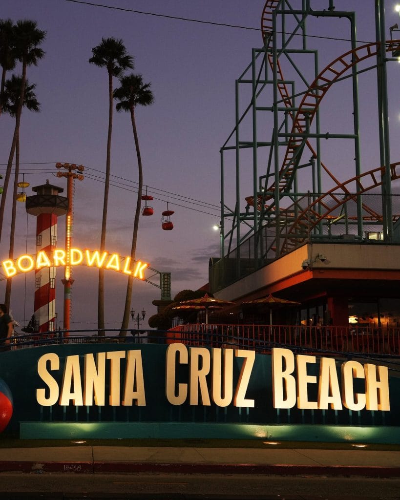Santa Cruz Beach Boardwalk with rides and palm trees at sunset