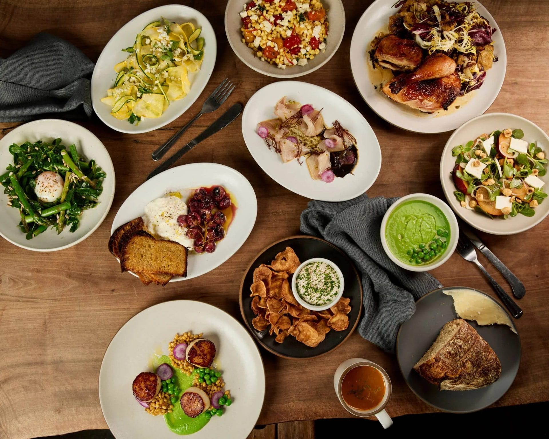 San Francisco Restaurants table spread with roasted chicken, salads, vegetables, bread, dip, and other shared dishes on a wooden table.