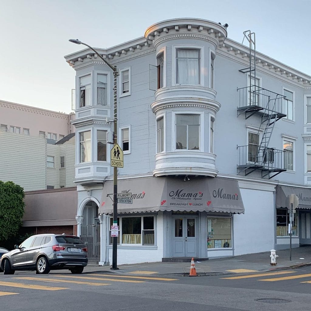 San Francisco Restaurants exterior showing Mama’s breakfast and lunch spot on a corner building with bay windows, street parking, and a crosswalk.