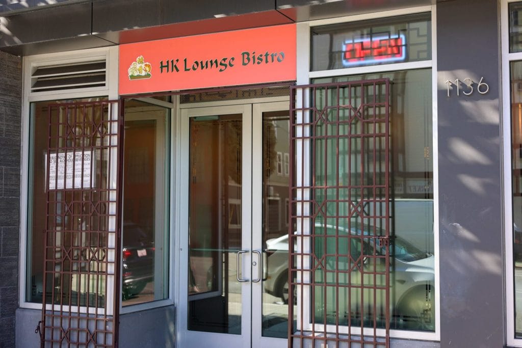 San Francisco Restaurants exterior showing HK Lounge Bistro with a red sign, glass doors, metal window grates, and street-facing entrance.
