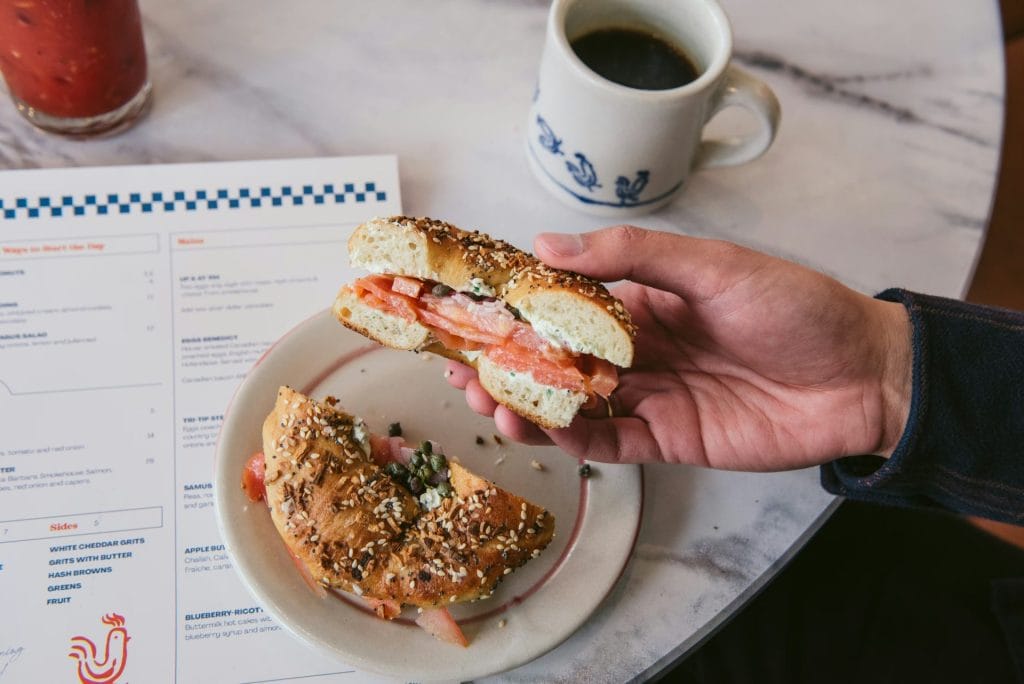 Father’s Day brunch at Early to Rise in San Francisco, featuring a smoked salmon bagel sandwich with coffee and a brunch menu on the table.