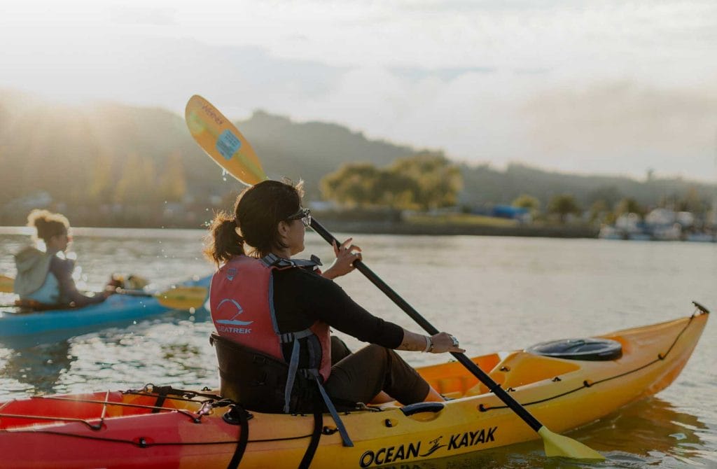 Person kayaking on the water with a paddle and life jacket during a Sea Trek outing.