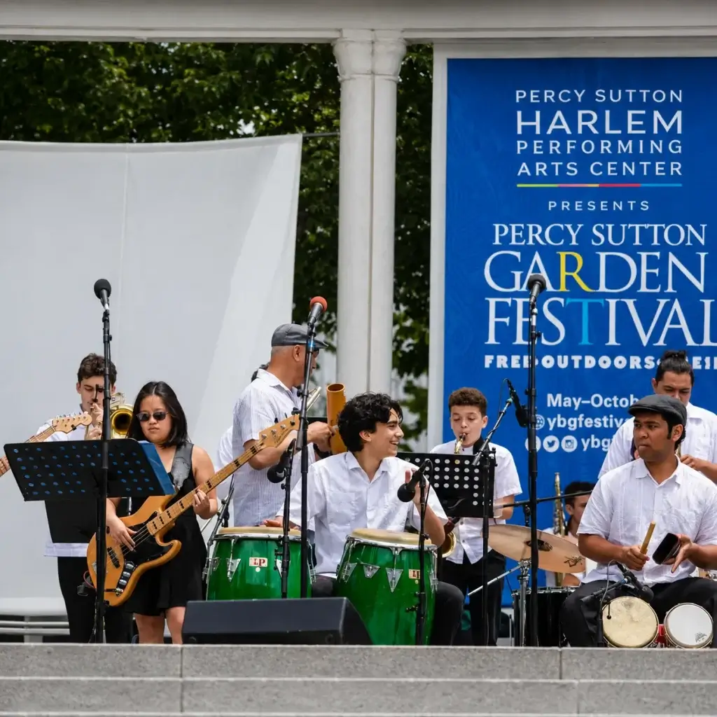 Musicians performing on an outdoor stage during a garden festival concert.