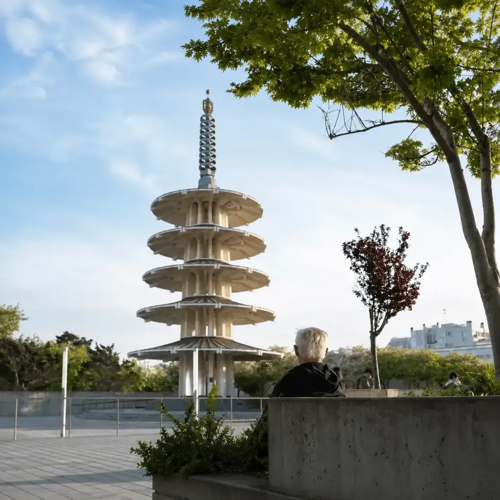 Person sitting near the Peace Pagoda in San Francisco Japantown with trees and open plaza space around them.