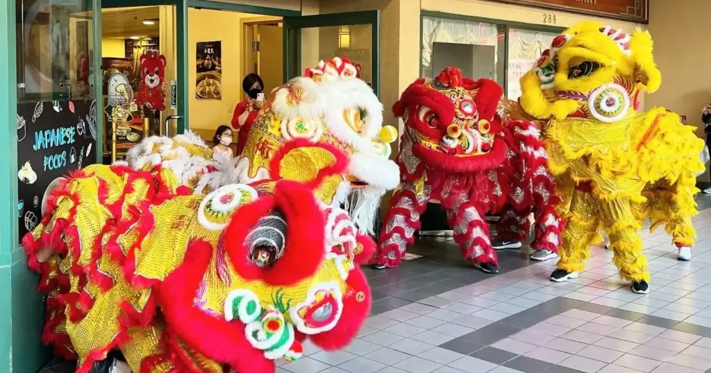 Lion dance performers in red, white, and yellow costumes during a cultural event in Japantown.