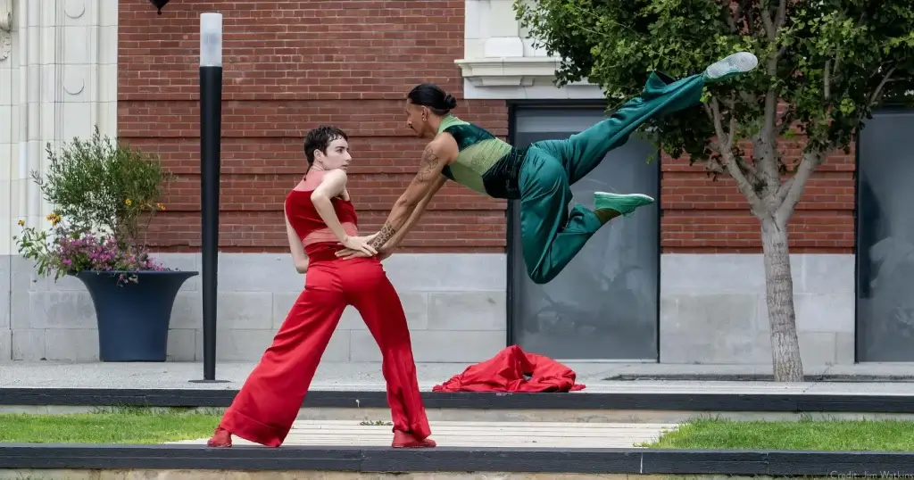 Two dancers perform outdoors during ChoreoFest at Yerba Buena Gardens in San Francisco, with one dancer leaping in the air and another standing in red.