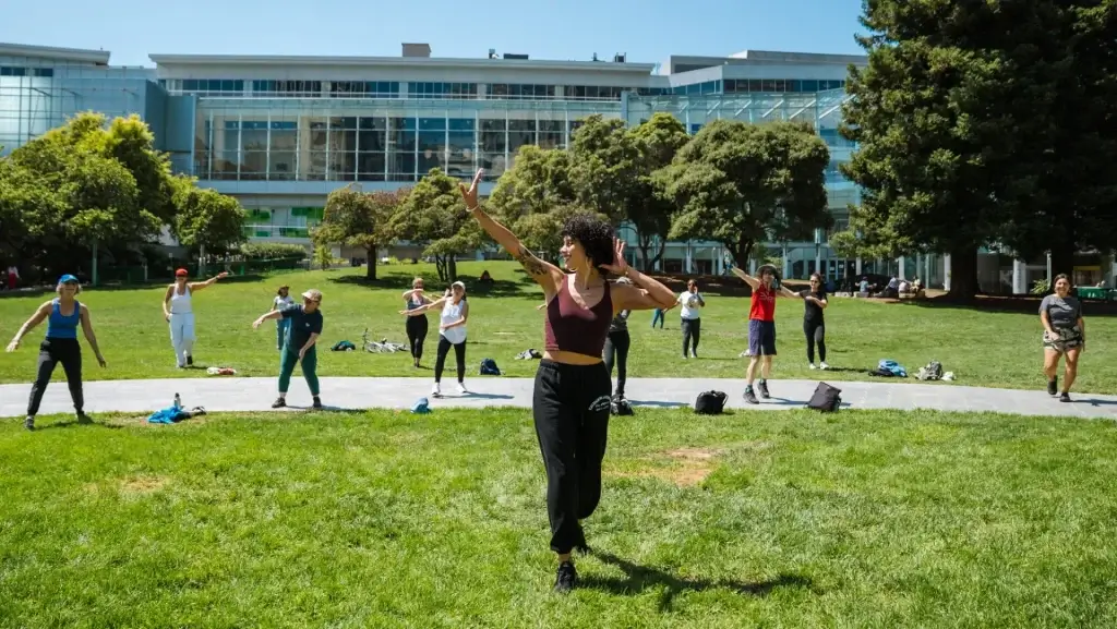 Outdoor Rhythm and Motion dance at Yerba Buena Gardens with participants following an instructor on the lawn.