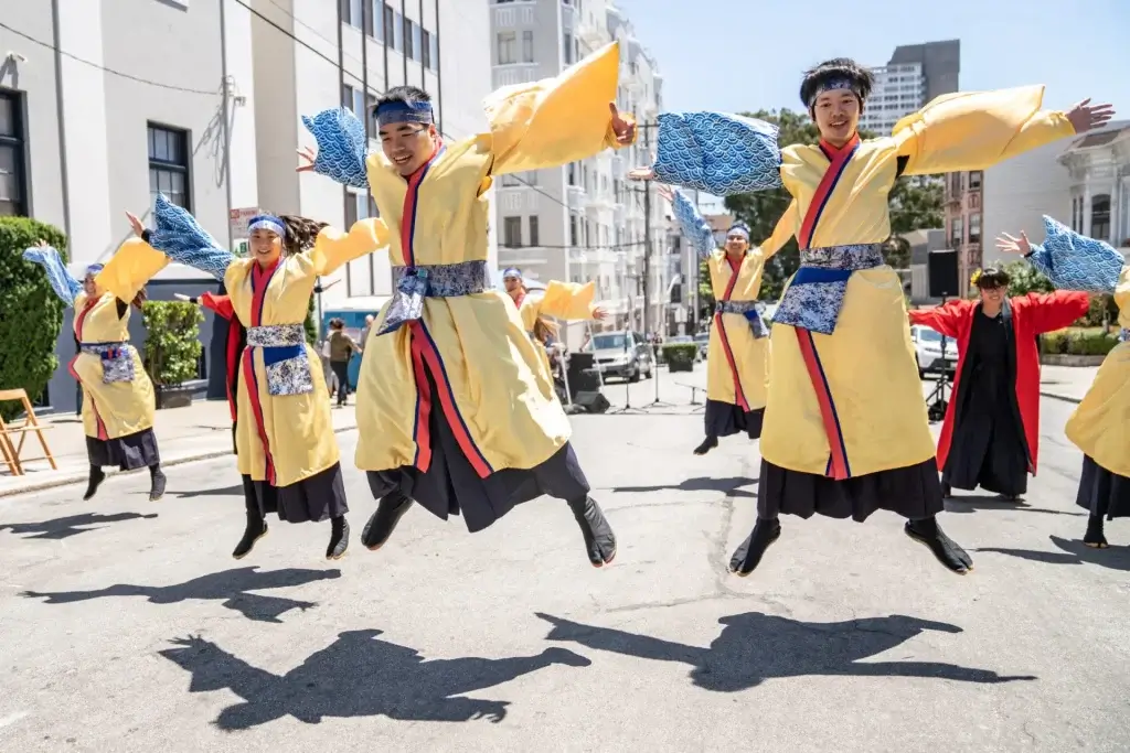 Dancers in yellow costumes jump during the Bon Odori Street Dance Festival in San Francisco.