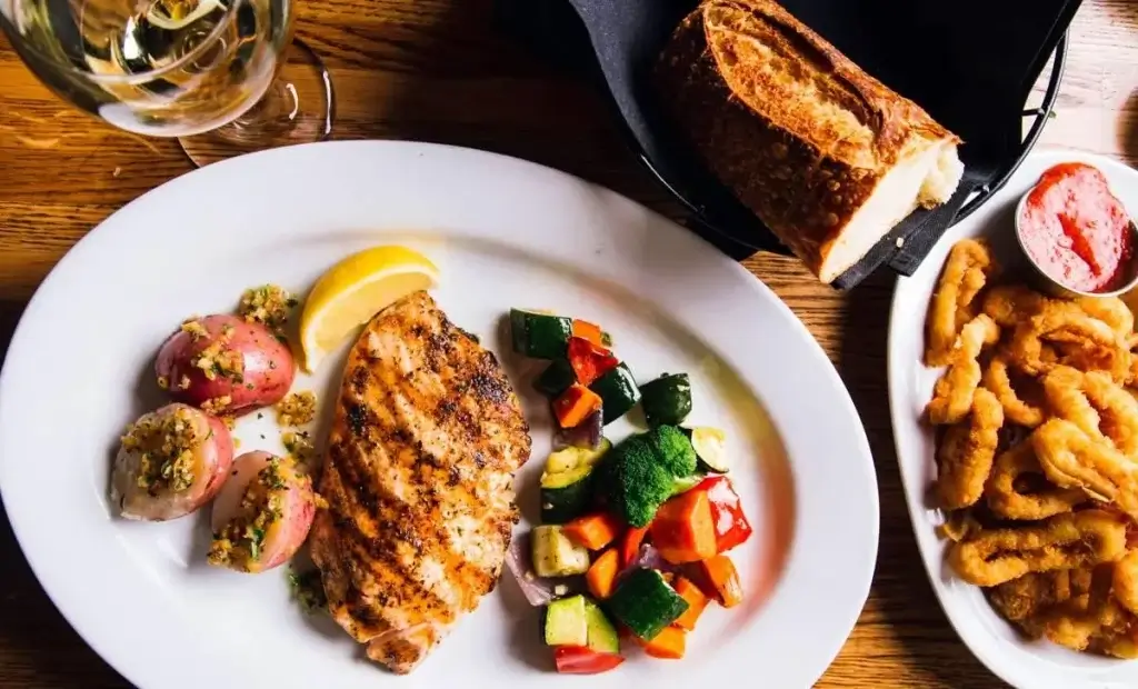 grilled salmon paired with herb-roasted peppers and vegetables, fried calamari and sourdough bread,