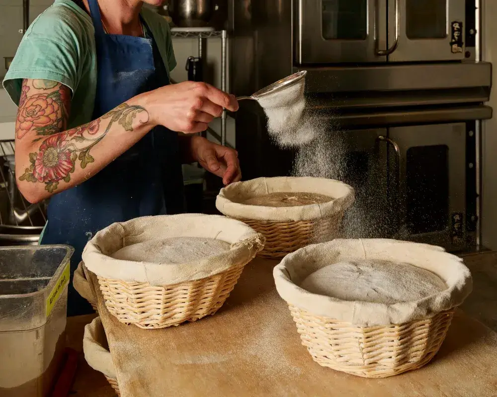 baker scoring sourdough resting on baskets, Outerlands restaurant in San Francisco