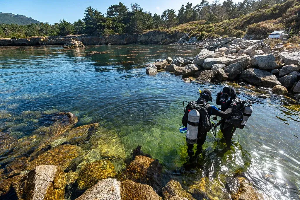 Two scuba divers preparing to descend into clear, turquoise waters at Point Lobos State Natural Reserve, Hidden gems along Highway 1