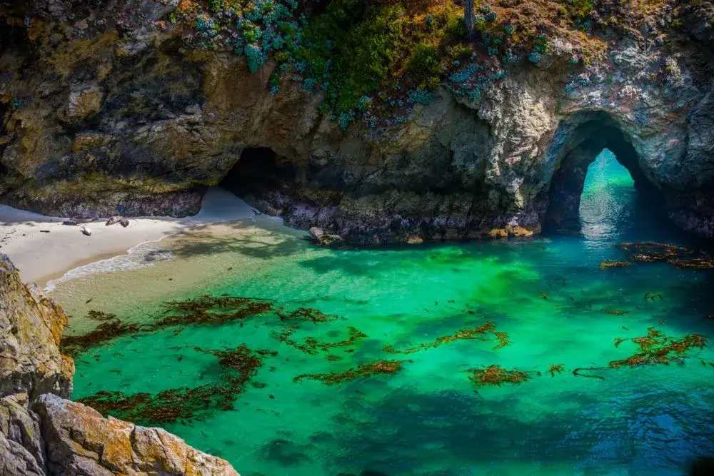 China Cove with emerald green water, a tiny pocket beach and a natural rock arch in Point Lobos, Hidden gems along Highway 1 road trip