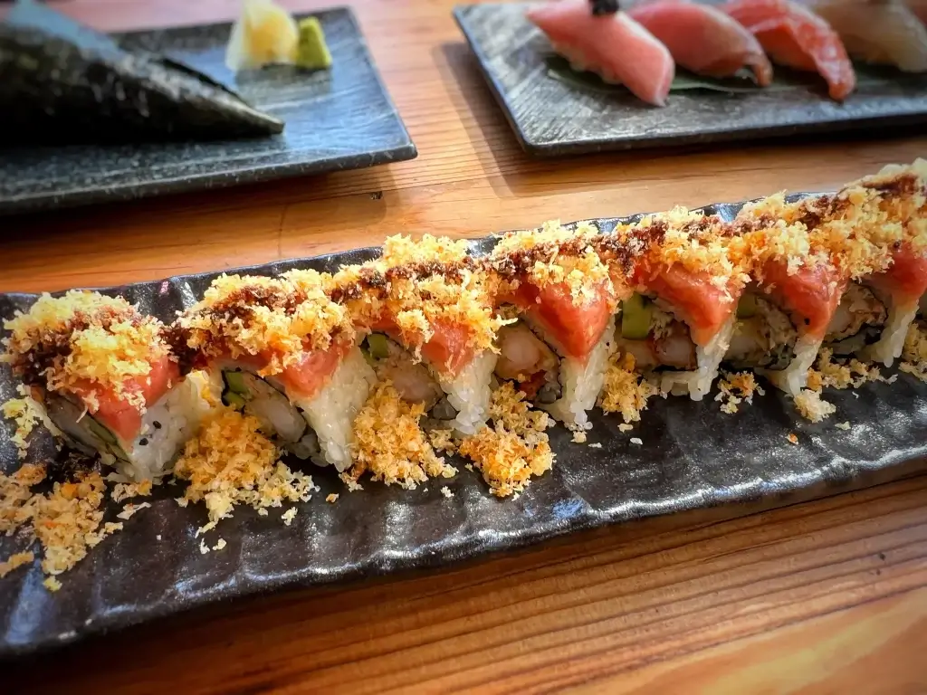 Crunchy Spicy Tuna Roll topped with salmon, garnished with tempura flakes