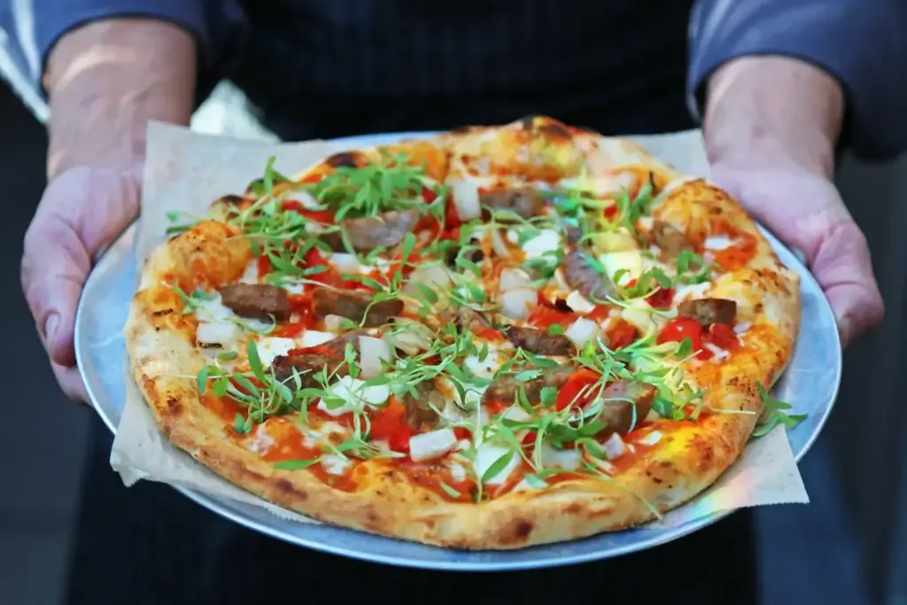 handcrafted Italian pizza topped with fresh arugula and meat pieces